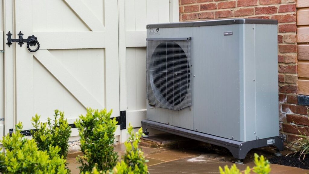 Outdoor heat pump unit installed beside house exterior wall
