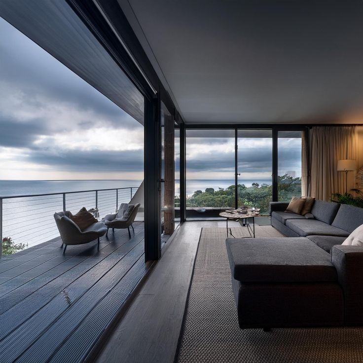 Modern oceanfront living room with large windows and balcony view