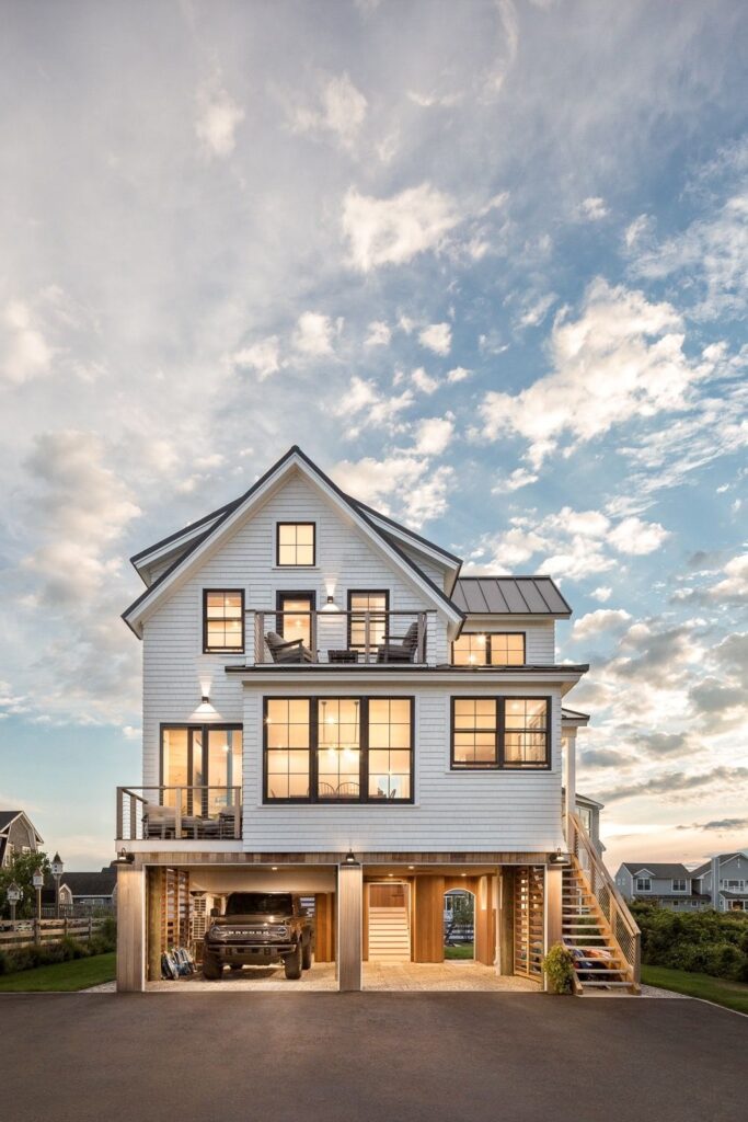 Modern coastal home exterior with large windows and elevated garage